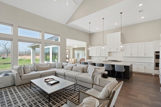 living room with a ceiling fan, visible vents, high vaulted ceiling, recessed lighting, and dark wood-type flooring