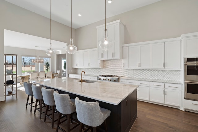 kitchen featuring a sink, backsplash, stainless steel appliances, a high ceiling, and white cabinets