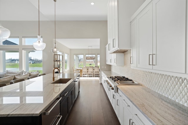 kitchen featuring decorative backsplash, white cabinets, stainless steel appliances, and a sink