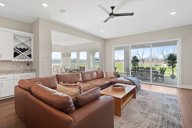 living area with visible vents, ceiling fan, a dry bar, recessed lighting, and wood finished floors