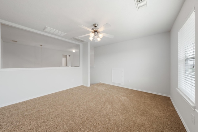 spare room featuring carpet floors, ceiling fan, and visible vents