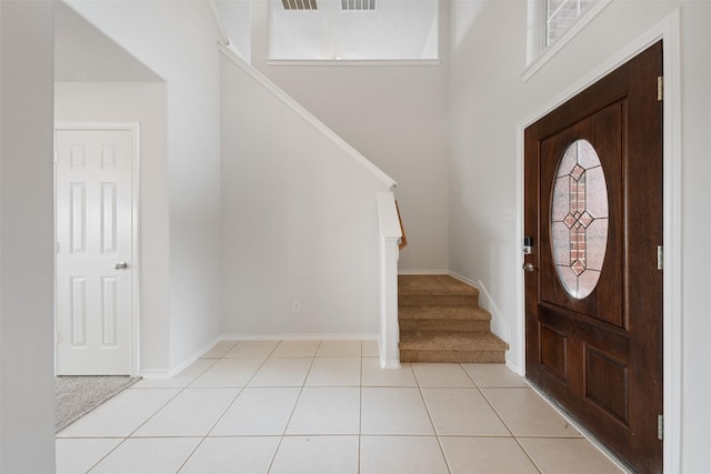 foyer entrance featuring light tile patterned floors, stairway, and baseboards