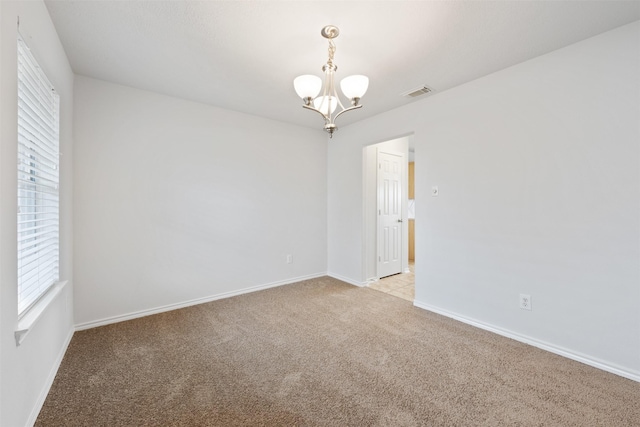 empty room with light carpet, baseboards, visible vents, and a chandelier