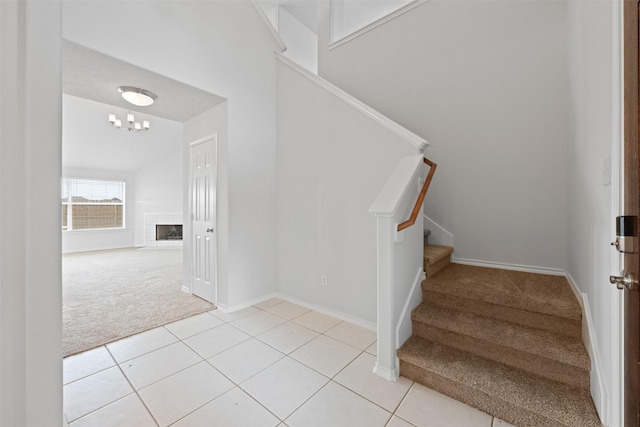 staircase with a tile fireplace, carpet flooring, baseboards, and tile patterned floors