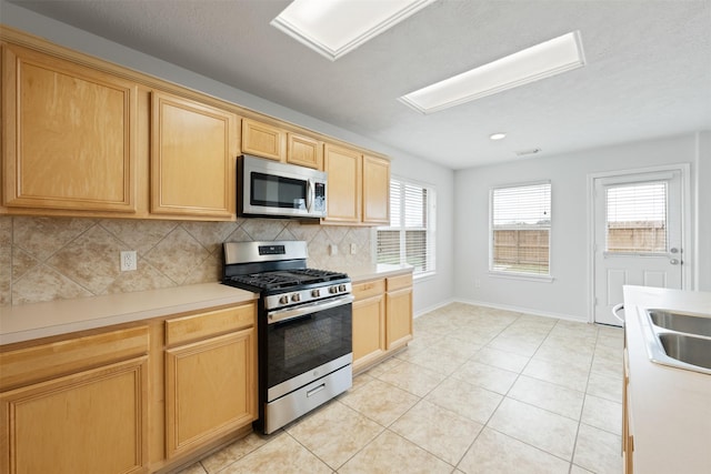 kitchen featuring appliances with stainless steel finishes, light countertops, light tile patterned floors, and tasteful backsplash