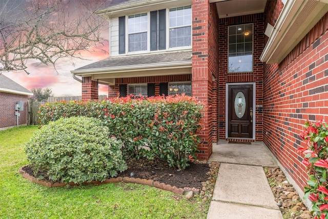 property entrance featuring roof with shingles and brick siding