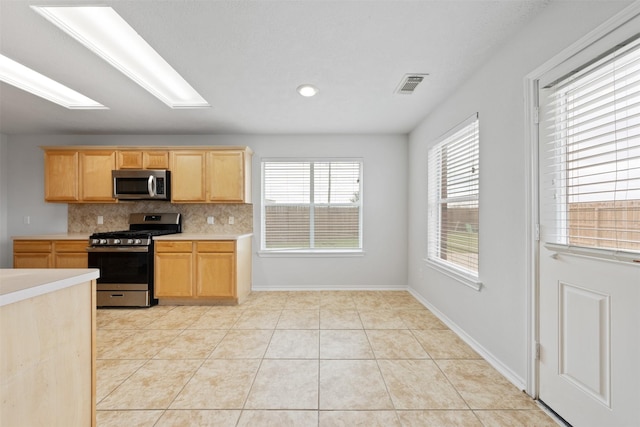 kitchen featuring light tile patterned floors, light countertops, visible vents, backsplash, and appliances with stainless steel finishes