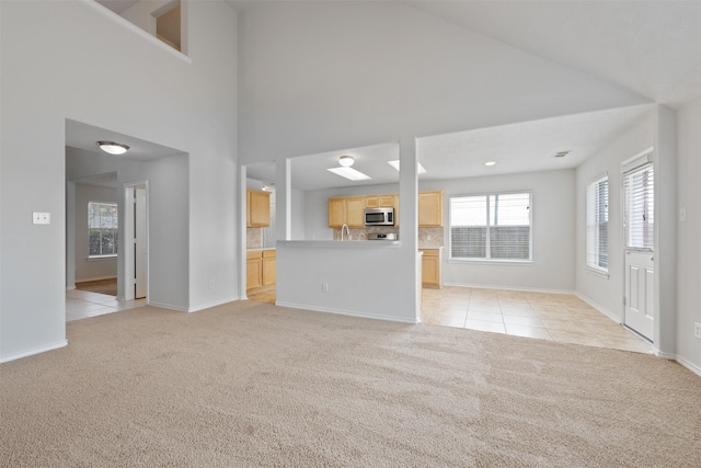 unfurnished living room with light carpet, light tile patterned floors, and a high ceiling