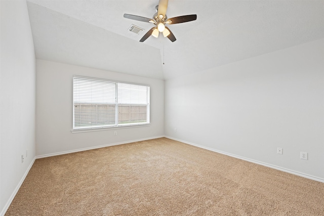 carpeted spare room with vaulted ceiling, visible vents, and baseboards