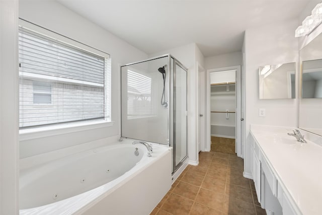 bathroom with tile patterned flooring, vanity, a spacious closet, a whirlpool tub, and a stall shower