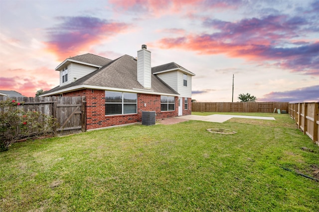 back of property with brick siding, a lawn, and a fenced backyard