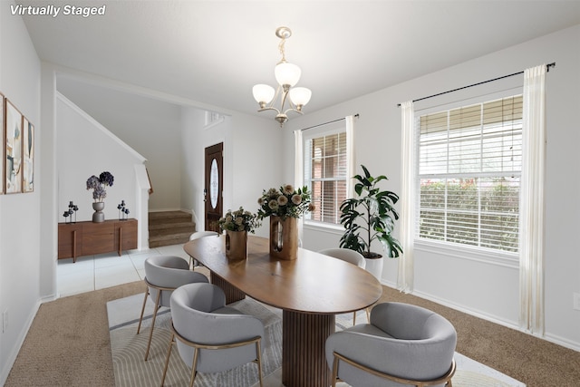 dining space featuring a healthy amount of sunlight, stairs, a notable chandelier, and light carpet