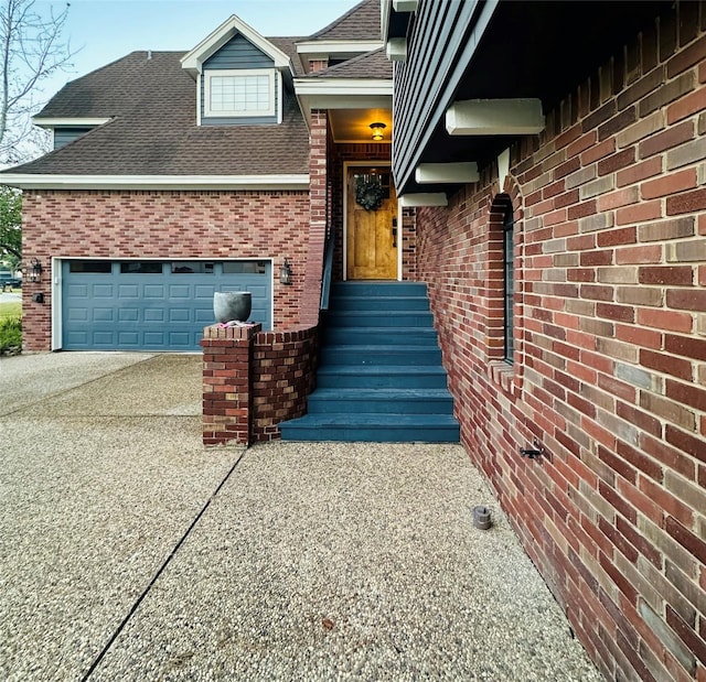 entrance to property with a garage, roof with shingles, concrete driveway, and brick siding