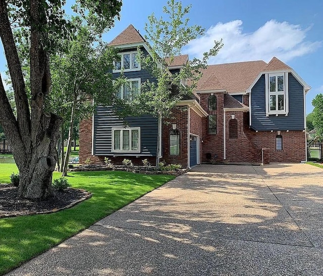 view of front of house with driveway, brick siding, and a front yard