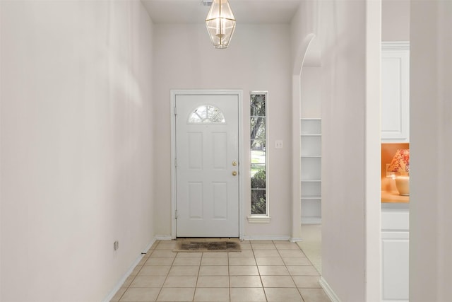 foyer entrance with baseboards, arched walkways, and light tile patterned flooring