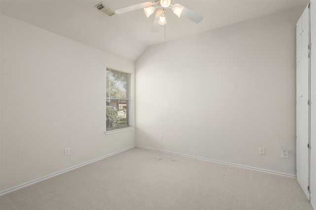 spare room with light carpet, baseboards, visible vents, a ceiling fan, and vaulted ceiling