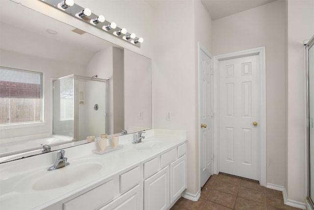 bathroom featuring a shower stall, double vanity, a sink, and tile patterned floors