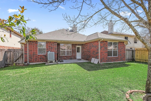 back of house with a fenced backyard, central AC, brick siding, a yard, and roof with shingles