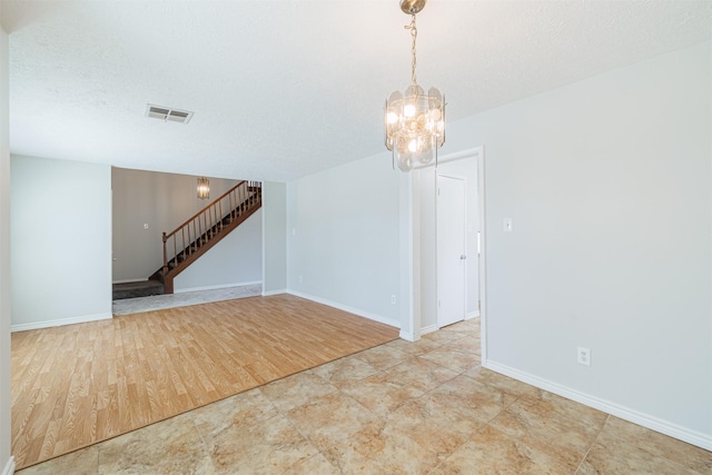 unfurnished room with visible vents, baseboards, stairs, wood finished floors, and a textured ceiling