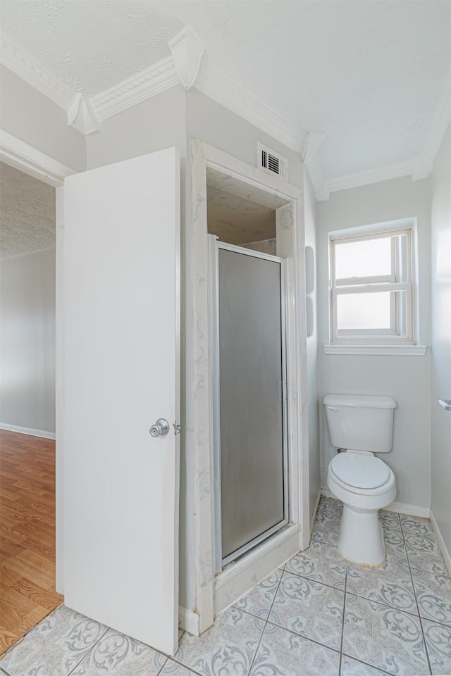 full bath featuring a stall shower, tile patterned flooring, a textured ceiling, crown molding, and toilet