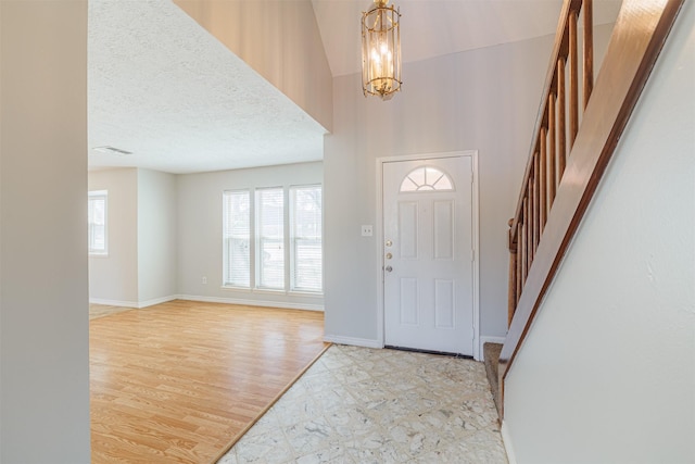 entrance foyer featuring visible vents, a notable chandelier, wood finished floors, baseboards, and stairs