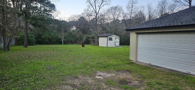 view of yard with an outbuilding, driveway, a storage shed, and a garage