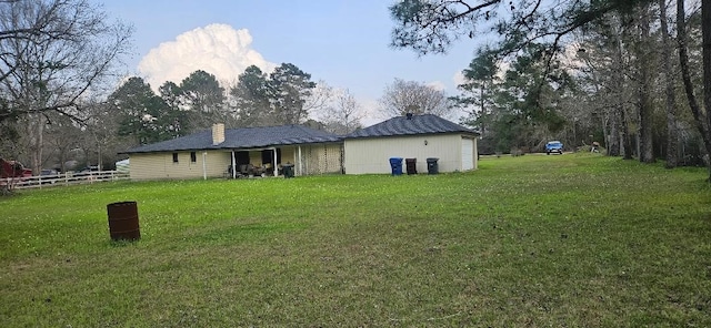 back of house featuring a yard, a chimney, and fence