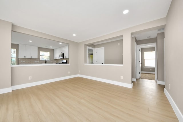 unfurnished living room featuring light wood finished floors, plenty of natural light, recessed lighting, and baseboards