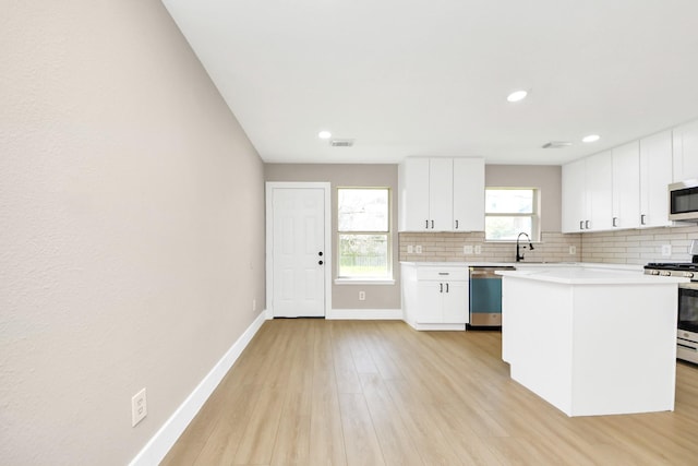 kitchen with stainless steel appliances, light wood finished floors, backsplash, and light countertops