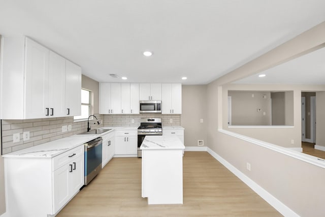 kitchen with light stone countertops, a sink, a center island, appliances with stainless steel finishes, and decorative backsplash