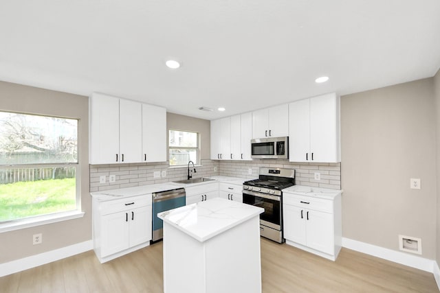 kitchen with stainless steel appliances, a sink, backsplash, and light stone countertops