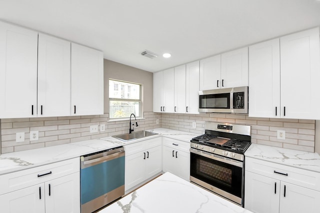 kitchen with light stone counters, visible vents, stainless steel appliances, and a sink