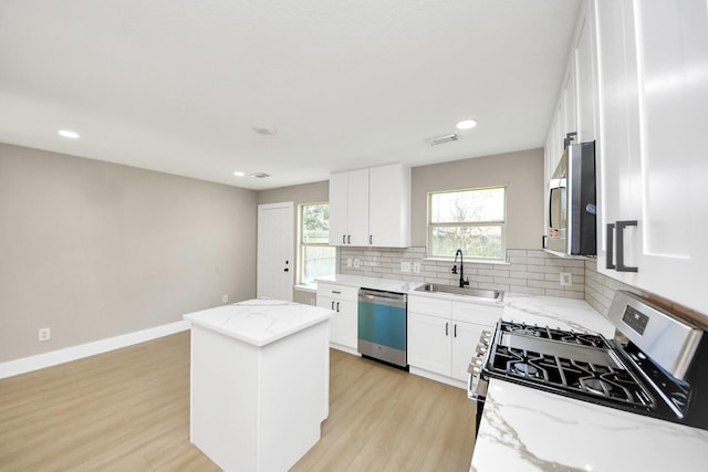 kitchen with tasteful backsplash, visible vents, appliances with stainless steel finishes, a sink, and a kitchen island