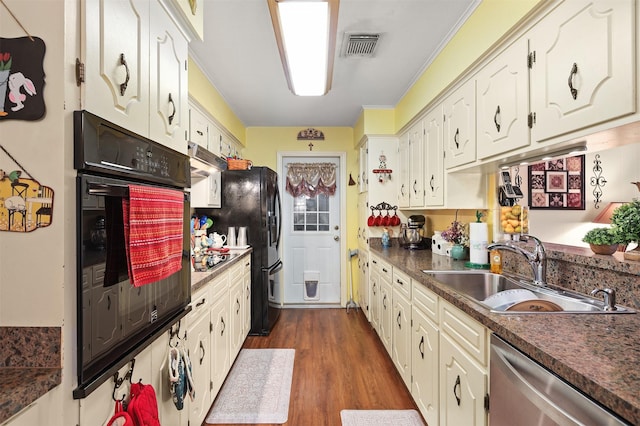 kitchen with black appliances, dark wood-type flooring, dark countertops, and a sink