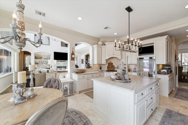 kitchen with visible vents, a center island, stone tile floors, arched walkways, and stainless steel appliances