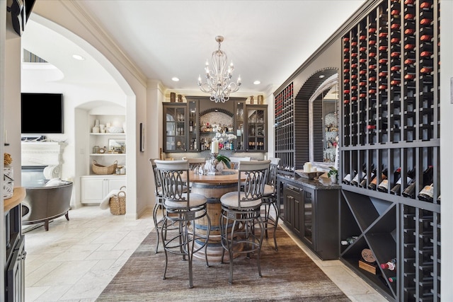 wine cellar with an inviting chandelier, stone tile flooring, built in features, and ornamental molding