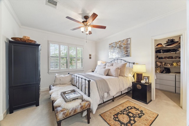 bedroom with visible vents, ceiling fan, ornamental molding, light carpet, and a walk in closet