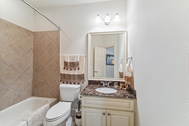 full bath with vanity, toilet, a textured wall, and shower / bath combination