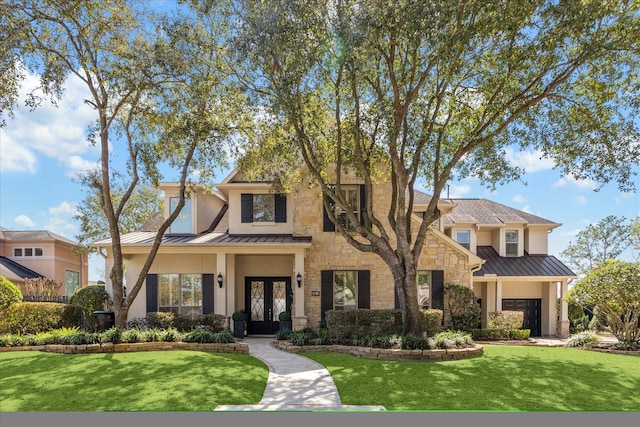 view of front of home with a front yard, a standing seam roof, stucco siding, french doors, and metal roof