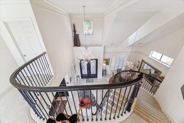 stairway with carpet floors, a high ceiling, a chandelier, and ornamental molding