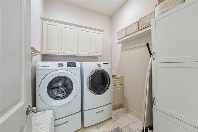 clothes washing area featuring cabinet space, washing machine and dryer, and stone finish flooring