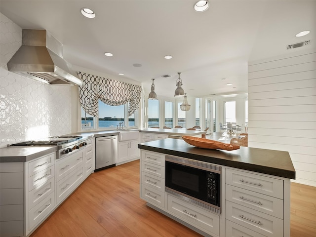 kitchen featuring stainless steel appliances, visible vents, plenty of natural light, and wall chimney exhaust hood