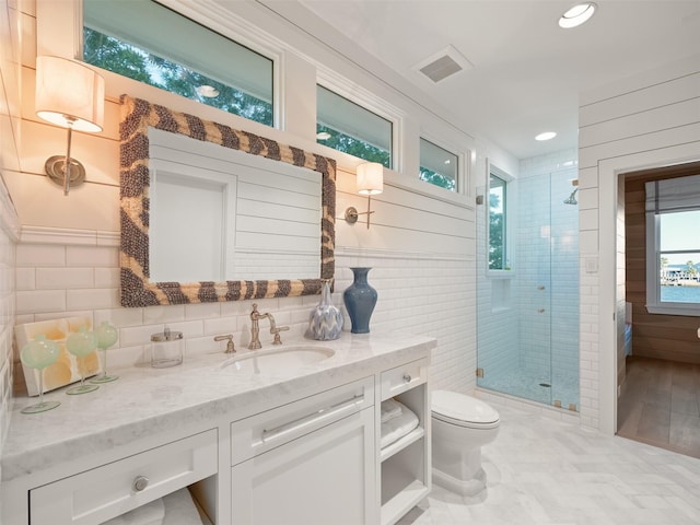 bathroom with toilet, visible vents, vanity, tile walls, and a shower stall