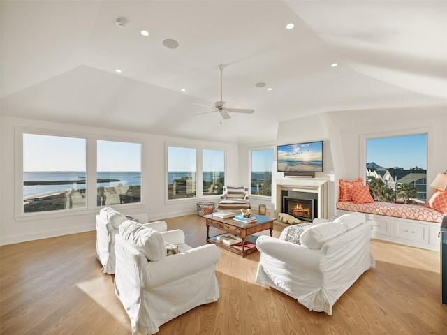 living room featuring recessed lighting, vaulted ceiling, a lit fireplace, and light wood finished floors