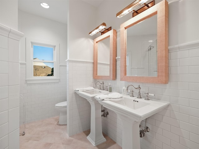 bathroom with toilet, wainscoting, tile walls, and tile patterned floors