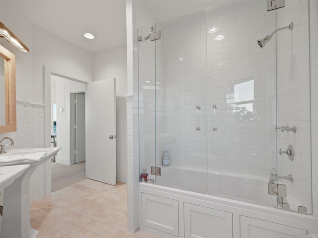 bathroom featuring shower / bath combination with glass door, a sink, tile walls, and tile patterned floors