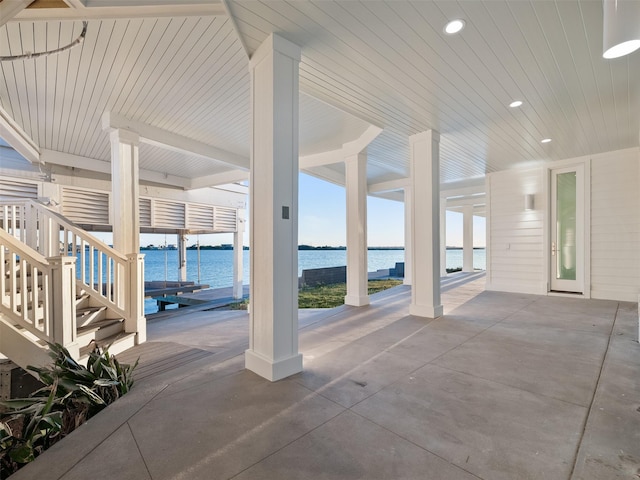 view of patio with a water view, stairs, and a dock