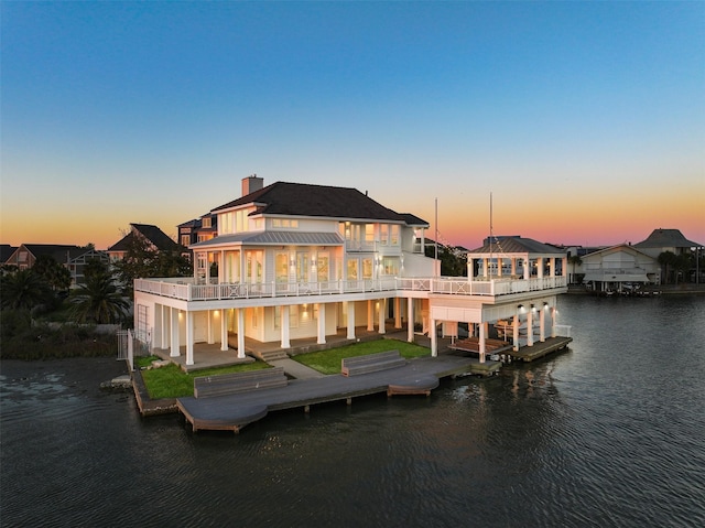 view of dock featuring a patio area, a water view, and a balcony