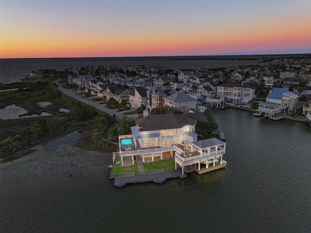 aerial view at dusk with a residential view and a water view