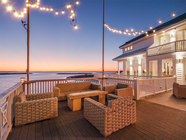 deck at dusk featuring a water view